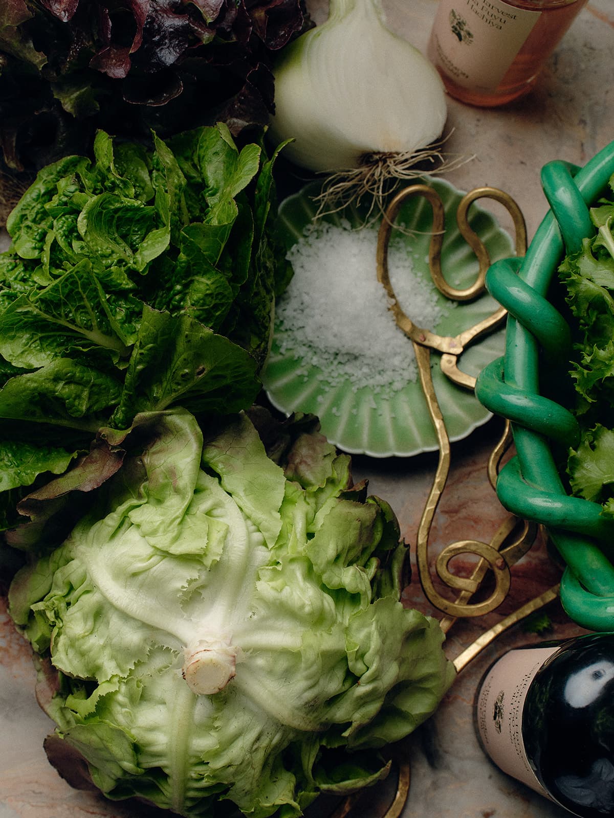 Lettuce and leafy greens lie scattered, accompanied by a small plate of salt.