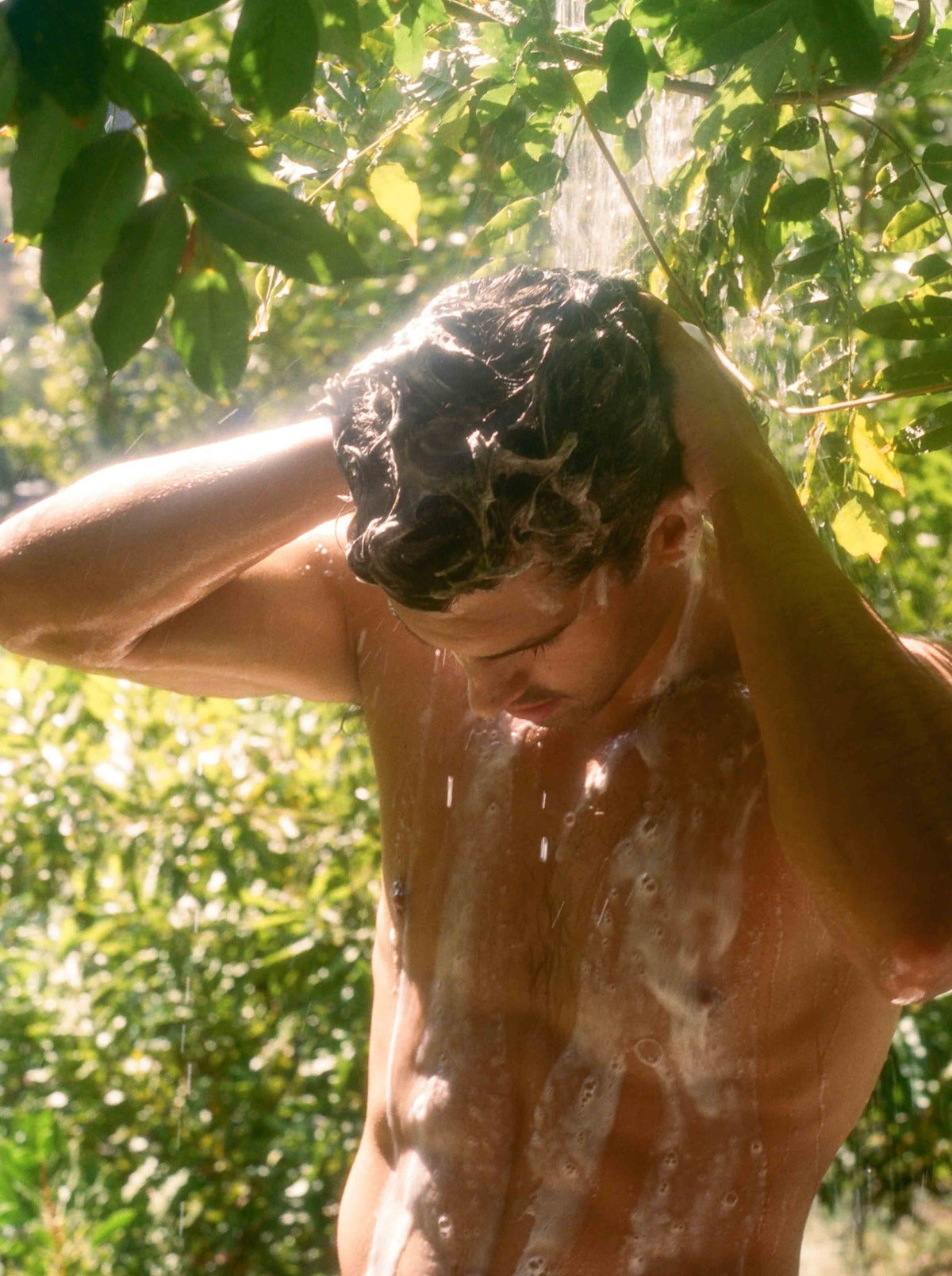 A person rinses soapy hair under a stream of water.