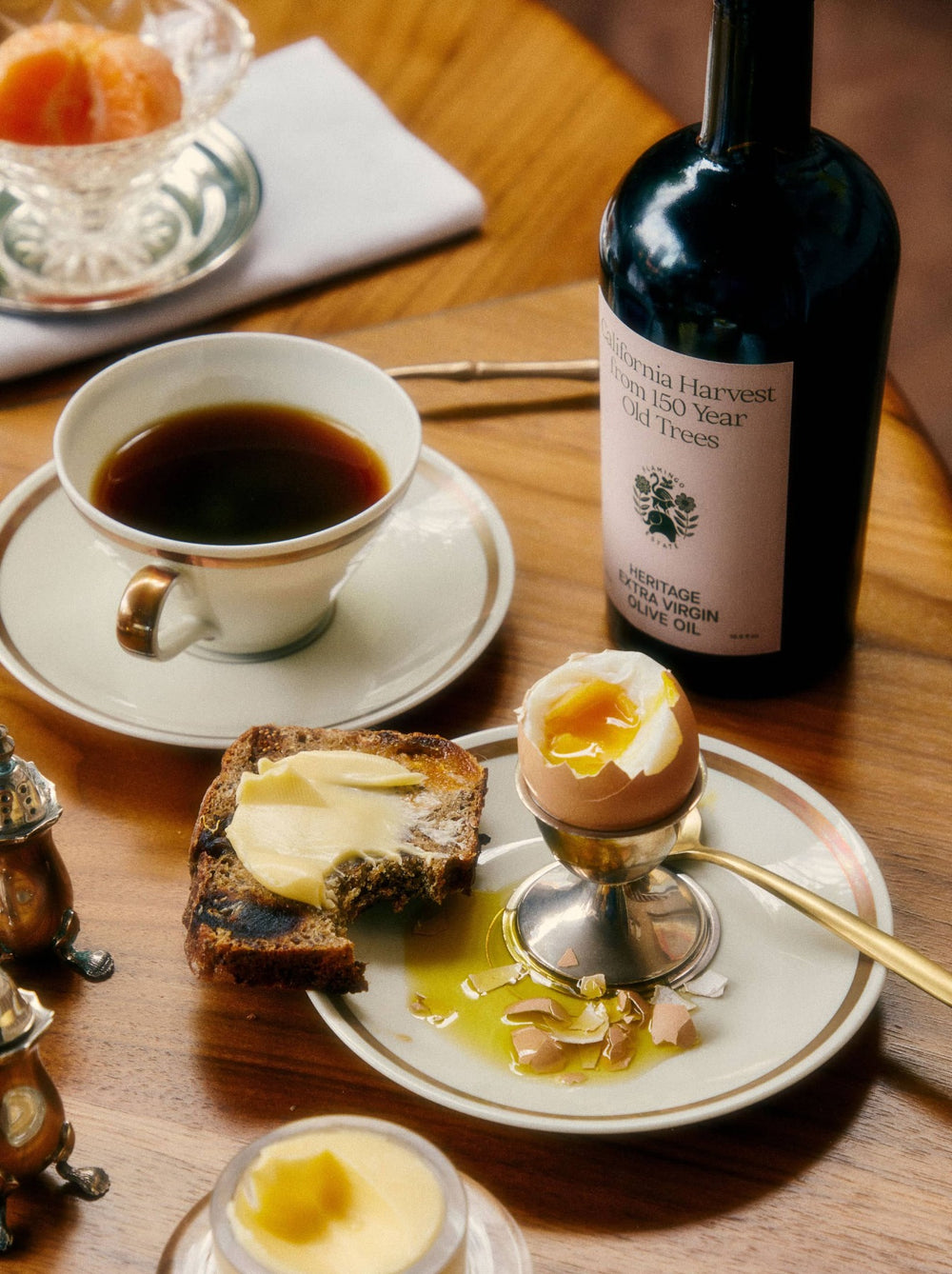Dippy Egg With Toast And Butter, A Coffee, And A Bottle Of Flamingo Estate Heritage Extra Virgin Olive Oil