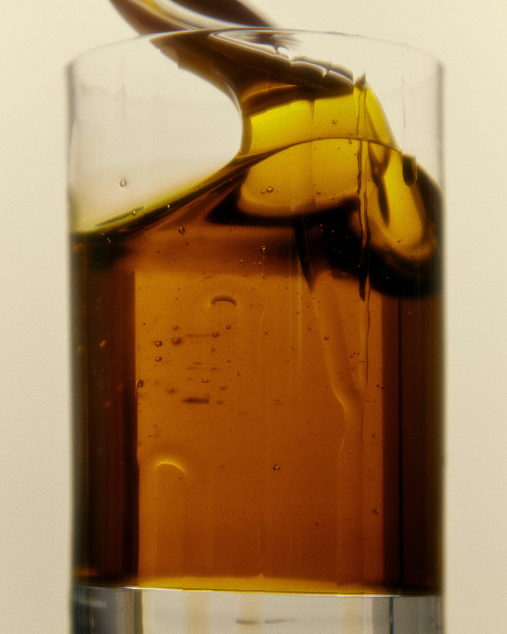 A close-up of golden Garlic Infused Olive Oil being poured from a bottle.