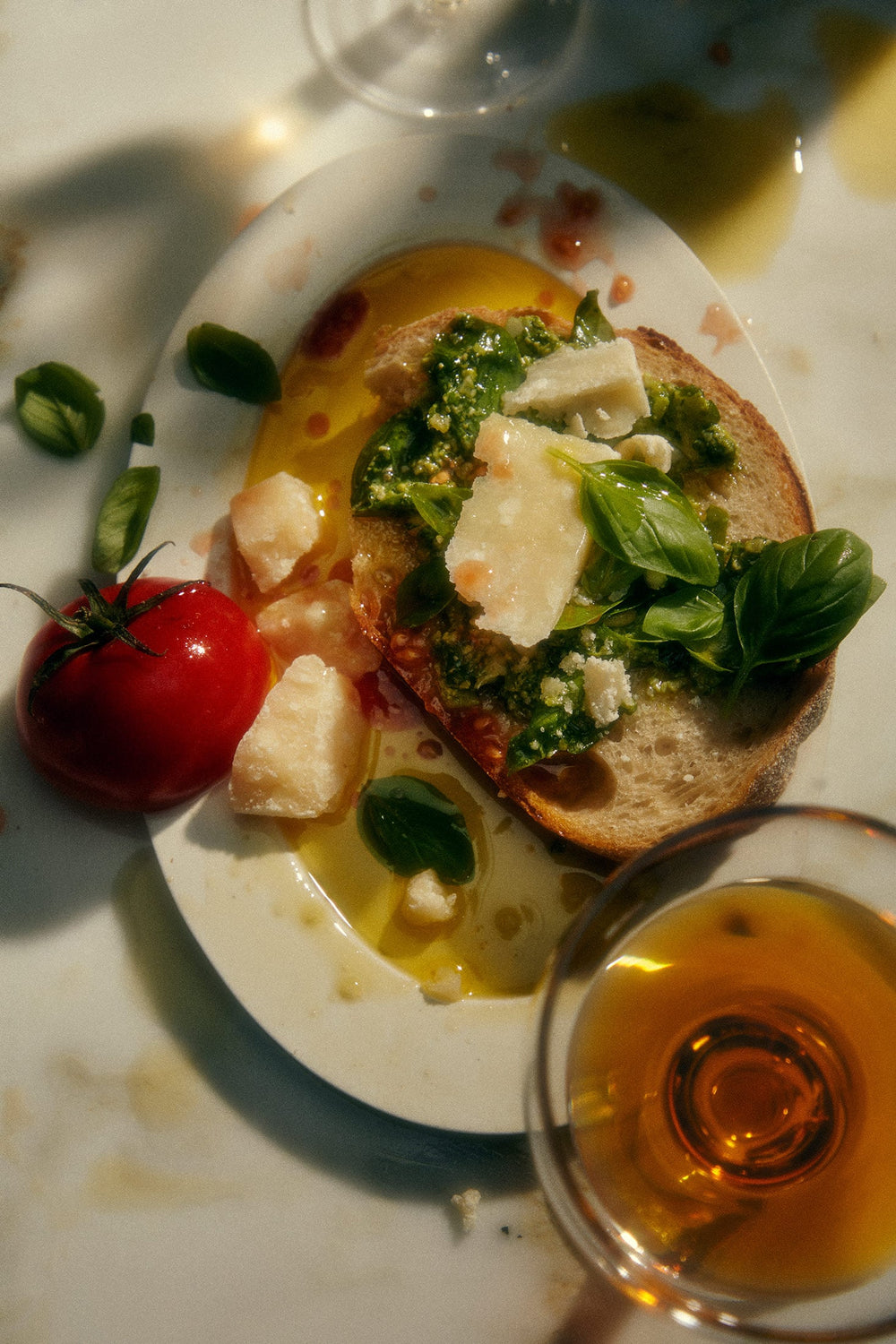 Garlic Infused Olive Oil next to a plated dish with fresh bread, tomatoes, and greens.