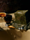 A large, green block of herbal soap rests on a glass tray.