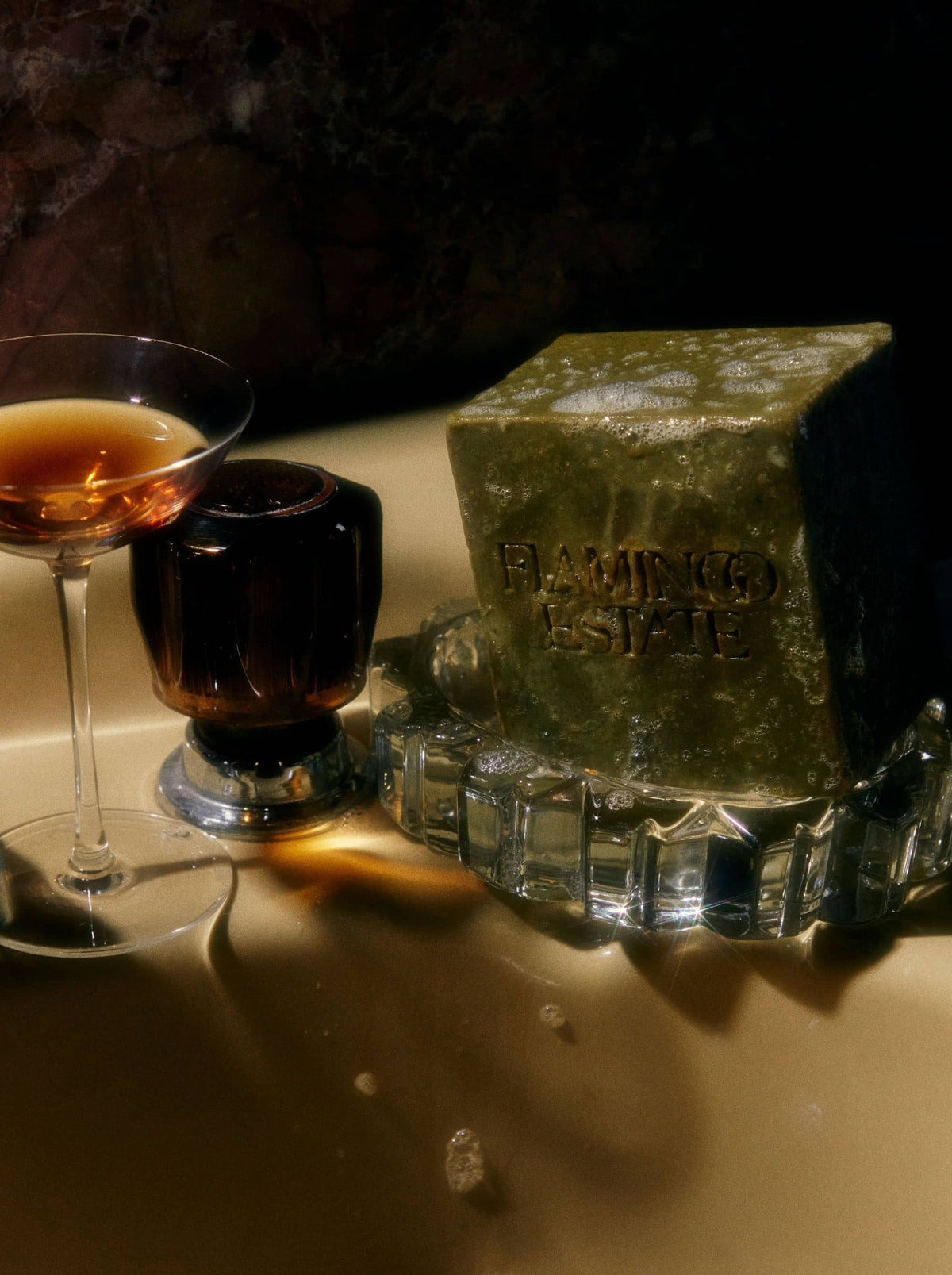 A large, green block of herbal soap rests on a glass tray.