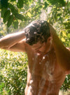A person rinses soapy hair under a stream of water.