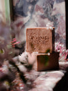 Two pink soap bars rest on a stone surface, adorned with small white flowers.