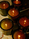 Candles flicker warmly, set in dark jars on a marbled surface.